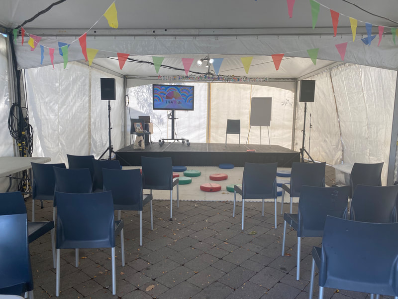 Performance tent at the festival, filled with chairs ahead of the event, and  festooned in colourful bunting.